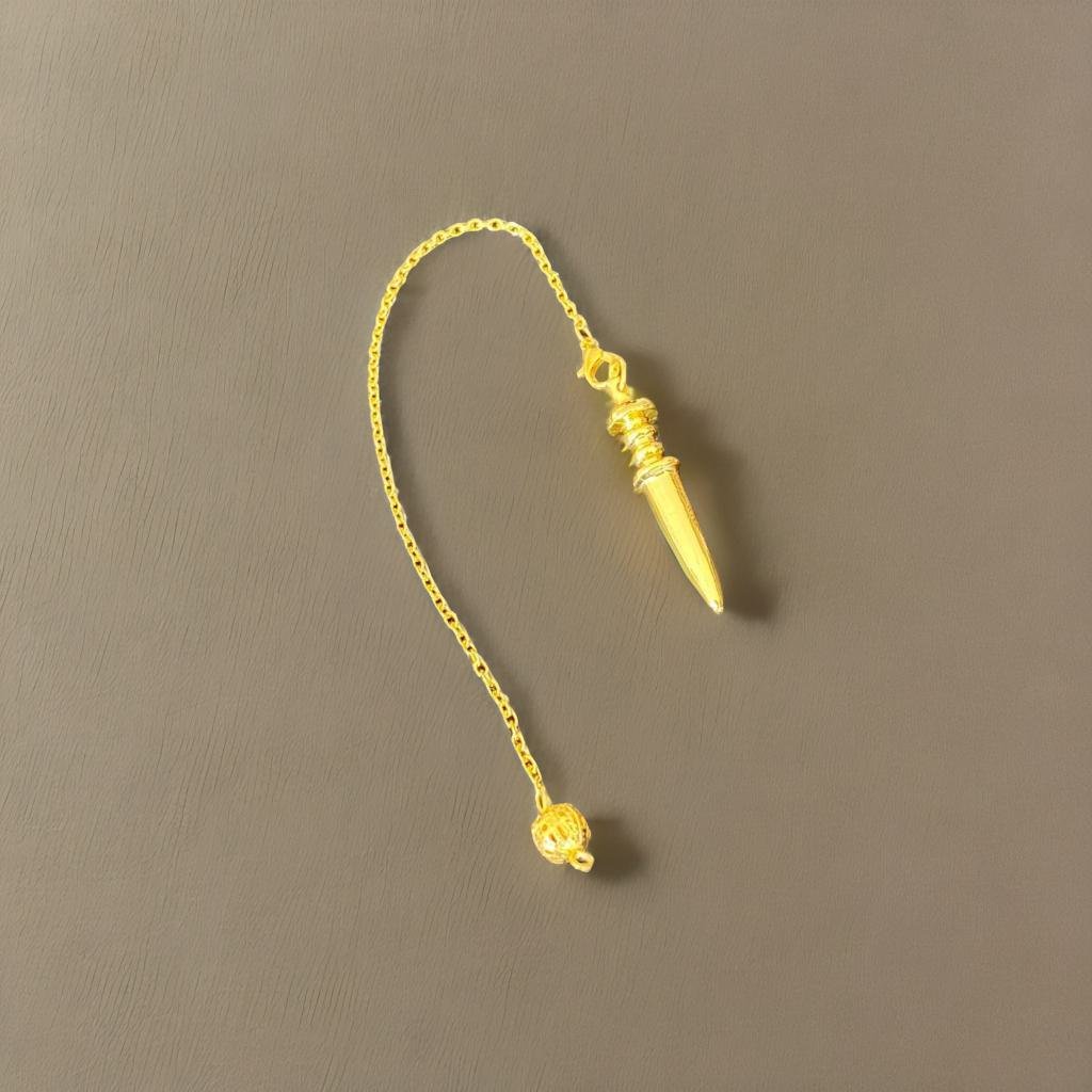 A gold pendulum with a pointed end and a small ball at the bottom rests on a gray surface.
