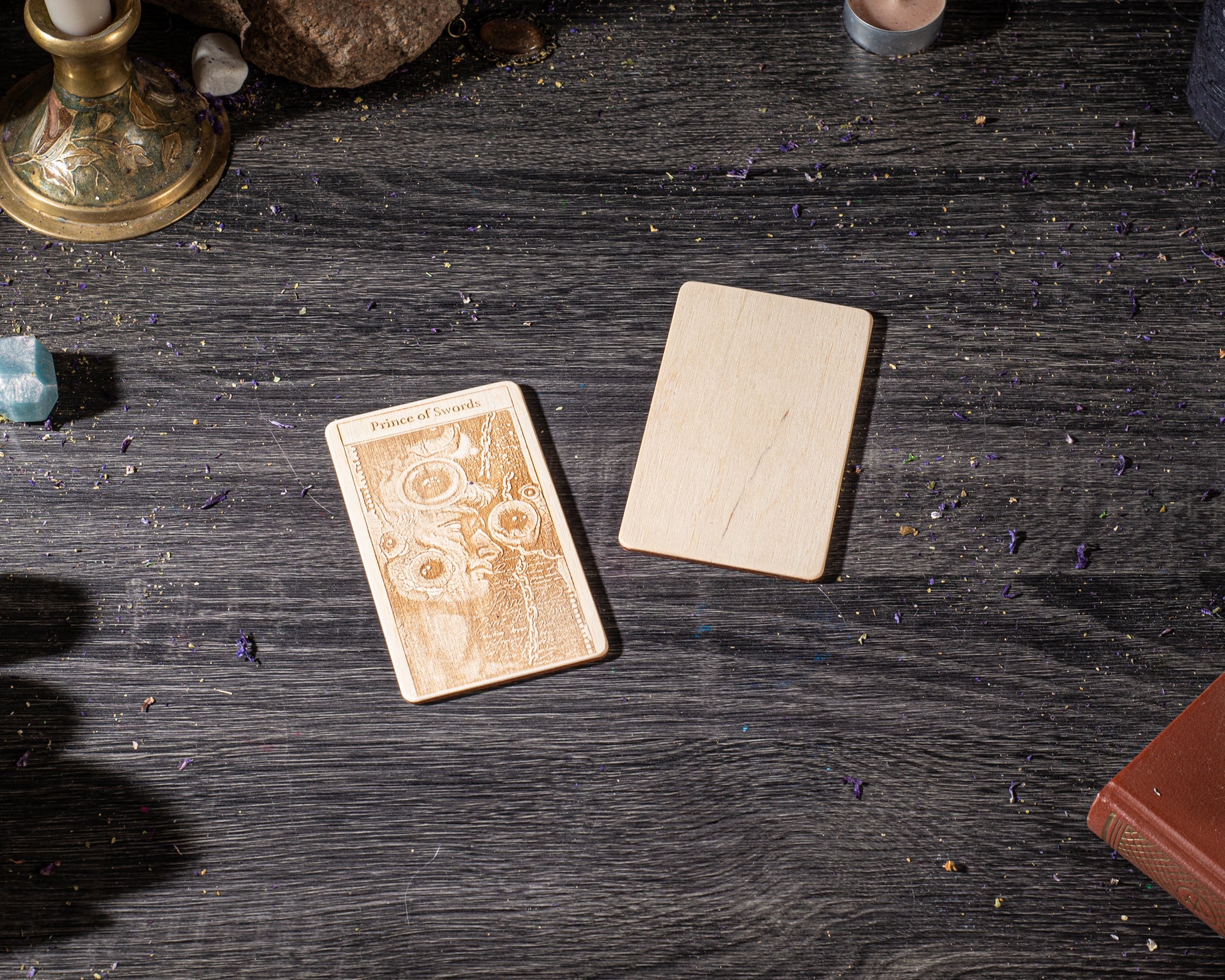 a wooden card with an embossed design, placed on a dark wooden surface alongside a wooden block and a book.