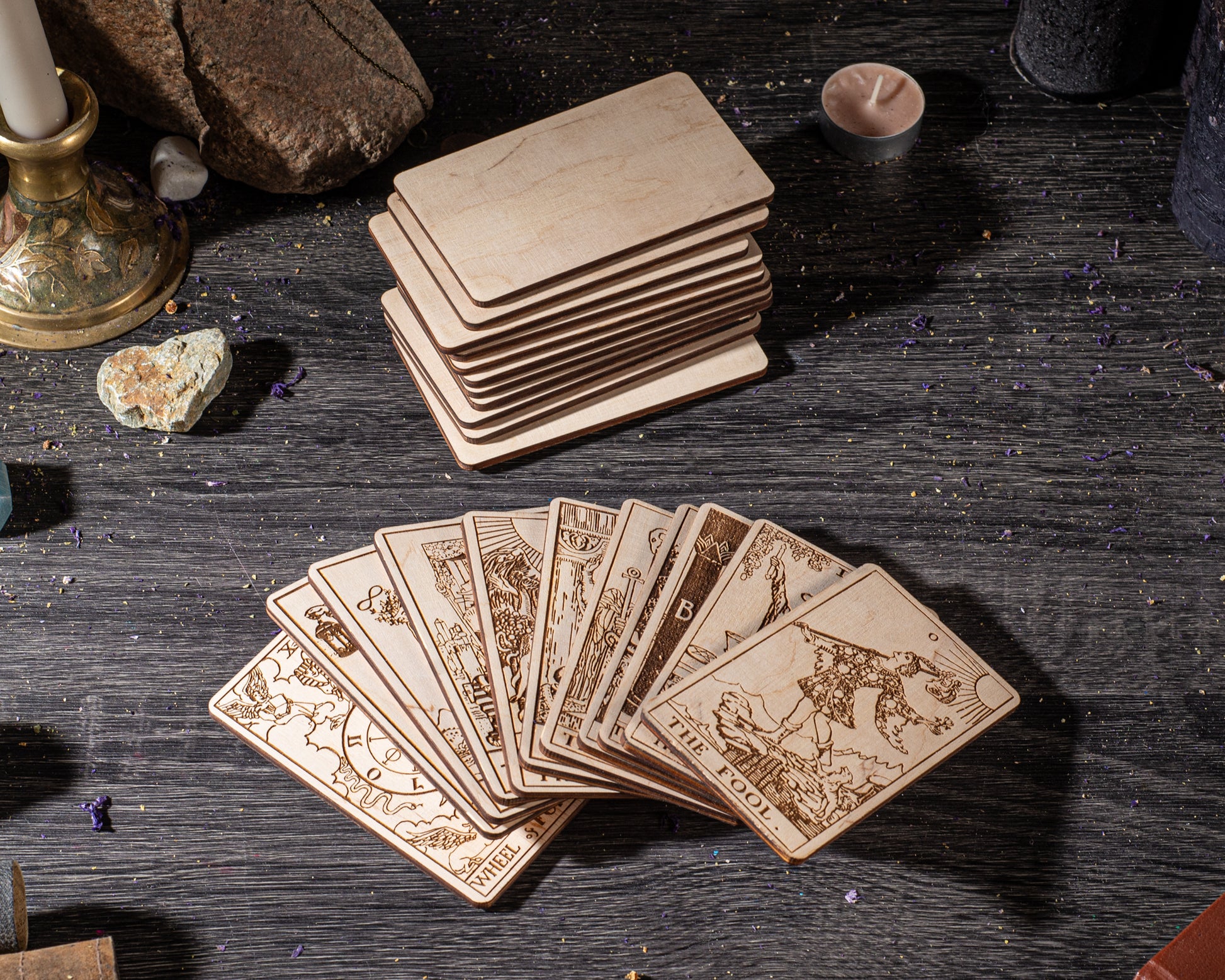 a collection of wooden tarot cards arranged on a dark wooden surface, with a stack of additional wooden cards in the background.