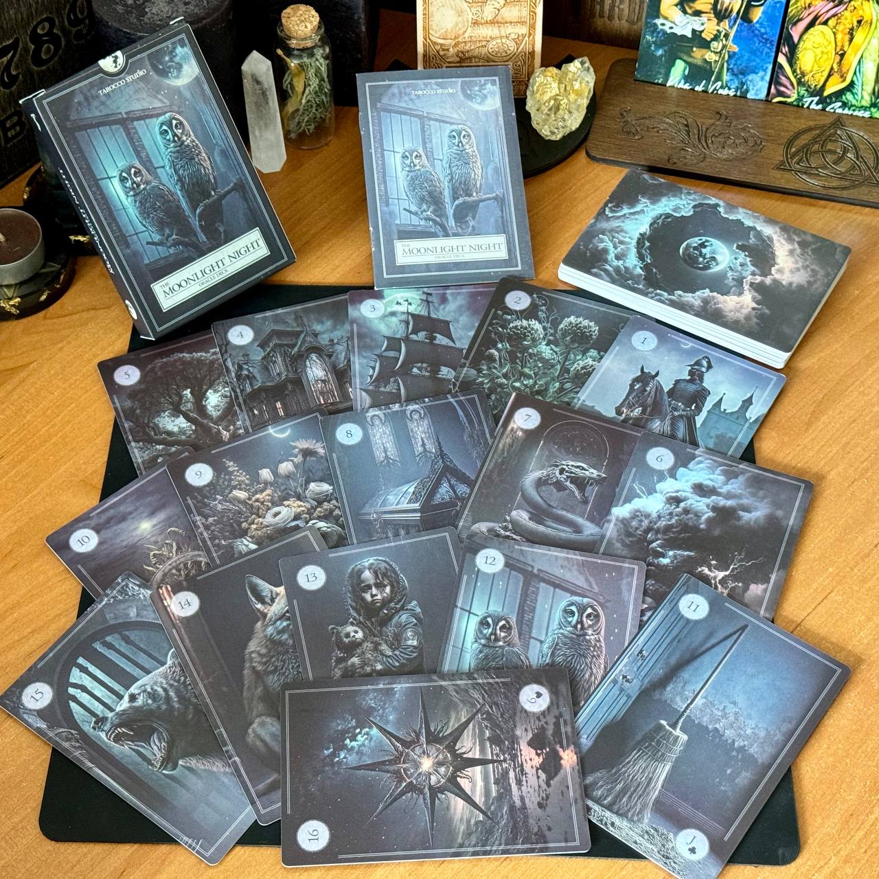 a collection of cards with various owl-themed illustrations, including owls, forests, and nighttime scenes. The cards are arranged on a wooden surface, with some of them placed on a mat.