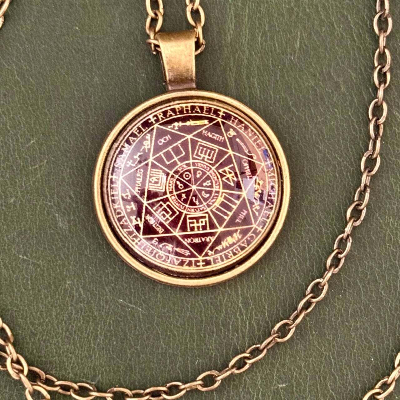 A pendant necklace with a circular pendant featuring a complex design and text.