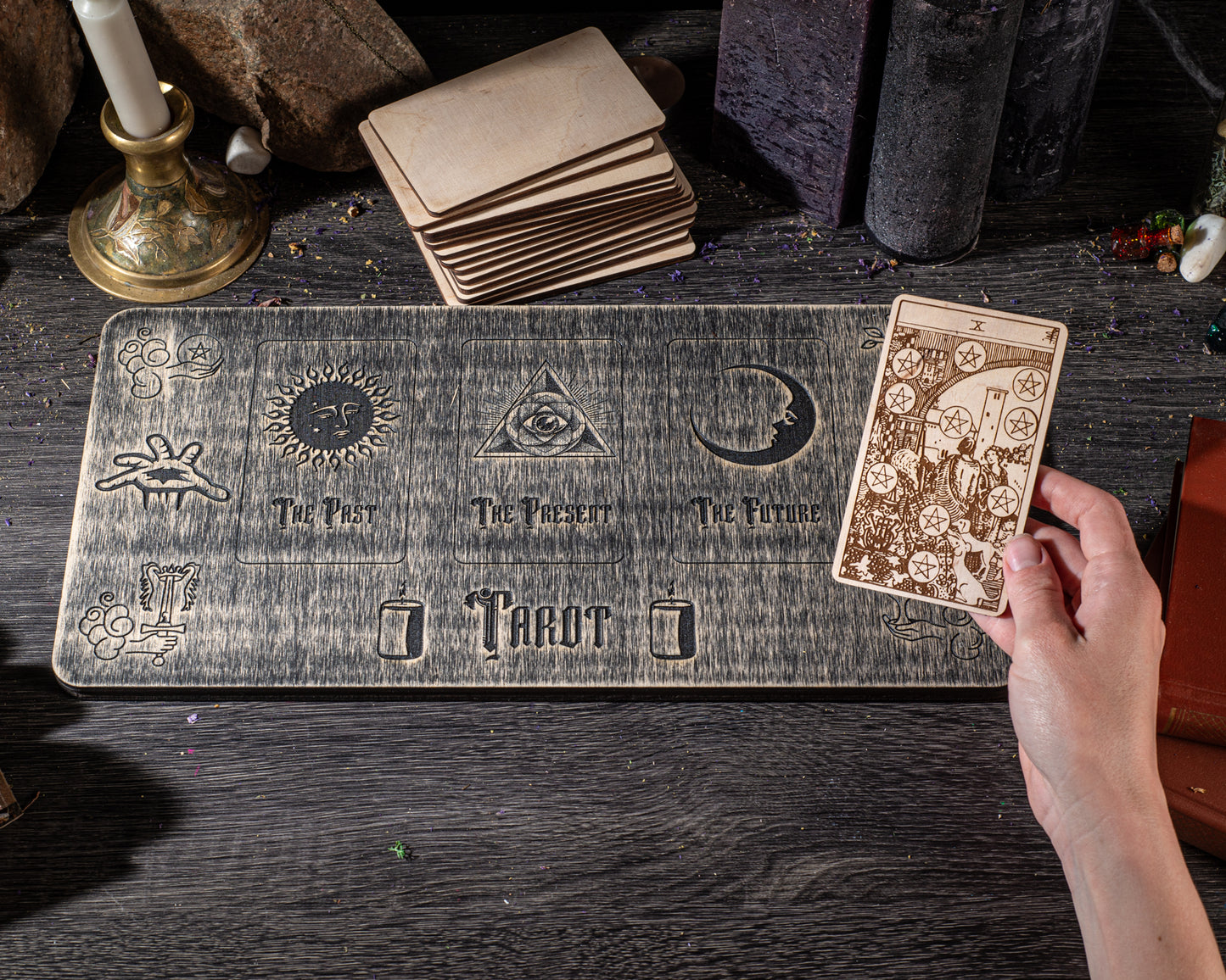 a wooden board with various tarot cards and symbols, including a hand holding a tarot card.