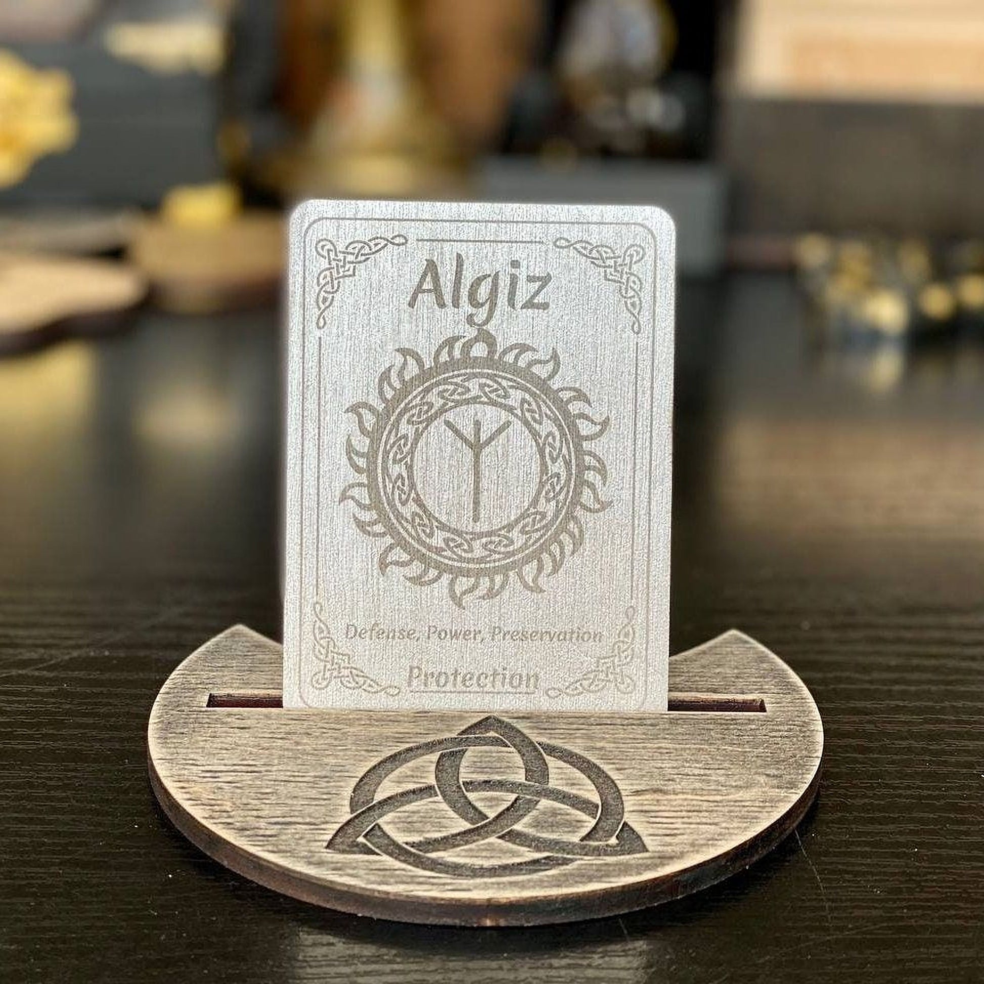 A metal card holder with a wooden base, displaying a metal card with the name Algiz and a design on it.