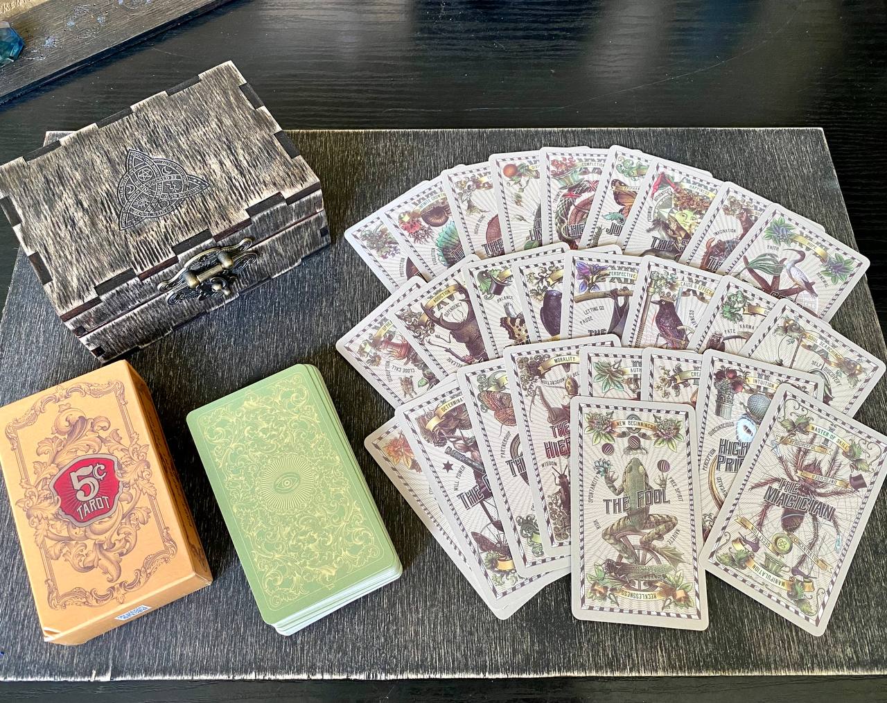 a collection of tarot cards and a wooden box, arranged on a wooden surface.