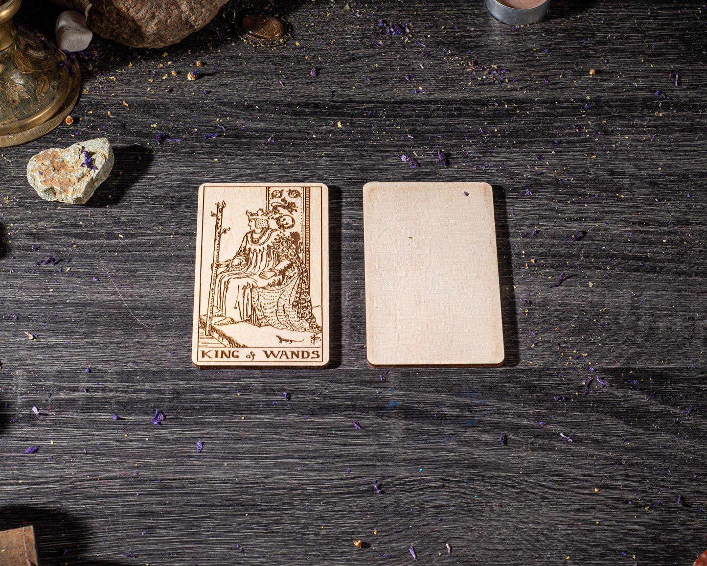 a wooden card with a design of a king and two blank cards placed on a wooden surface.