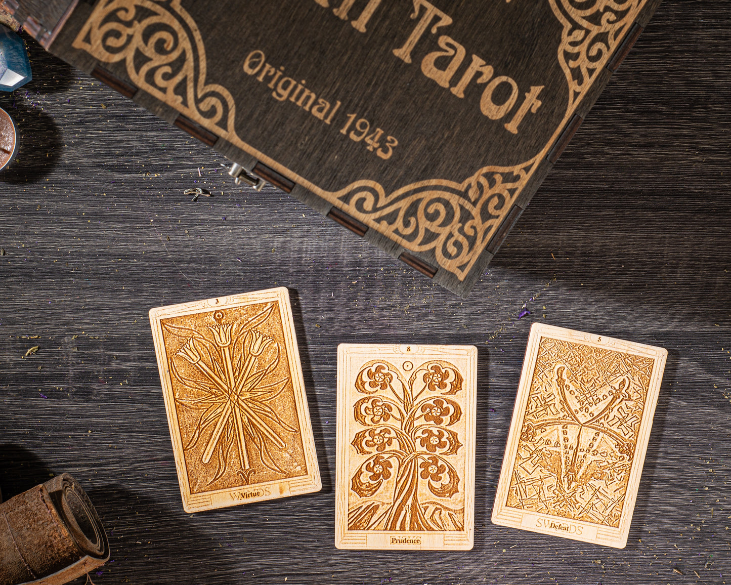 three wooden tarot cards with intricate designs, placed on a wooden surface alongside a wooden box with a decorative border.