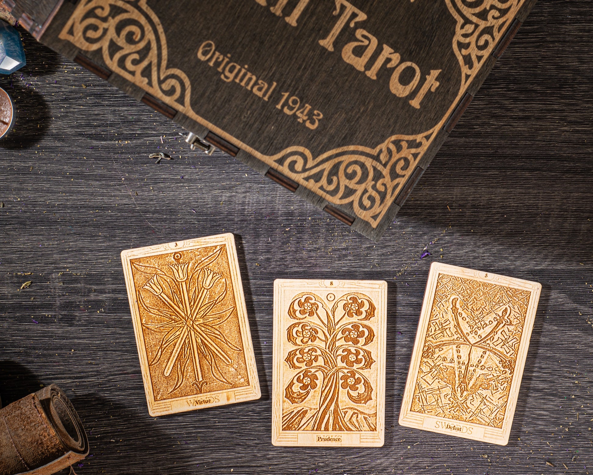 three wooden tarot cards with intricate designs, placed on a wooden surface alongside a wooden box with a decorative border.