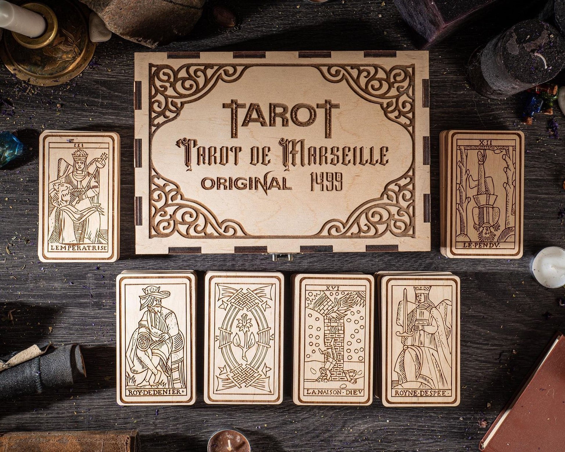a wooden box with the text "TAROT" and "Tarot de Marseille Original 1949" on it, along with six tarot cards arranged below it.