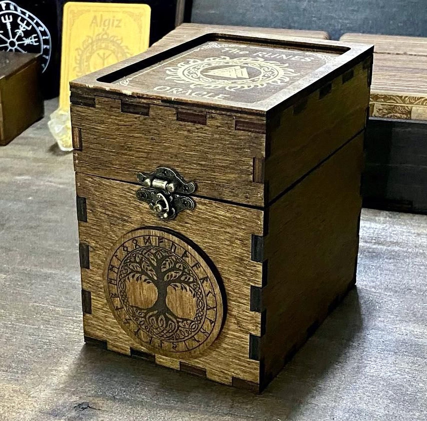 A wooden box with a tree design on it, sitting on a wooden surface.