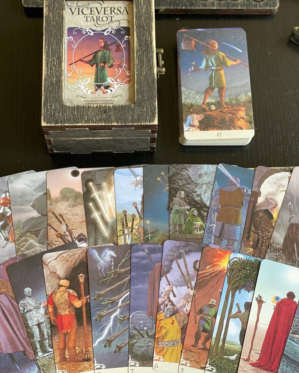 a collection of tarot cards and a wooden box, likely containing the "Viceversa Tarot" deck.
