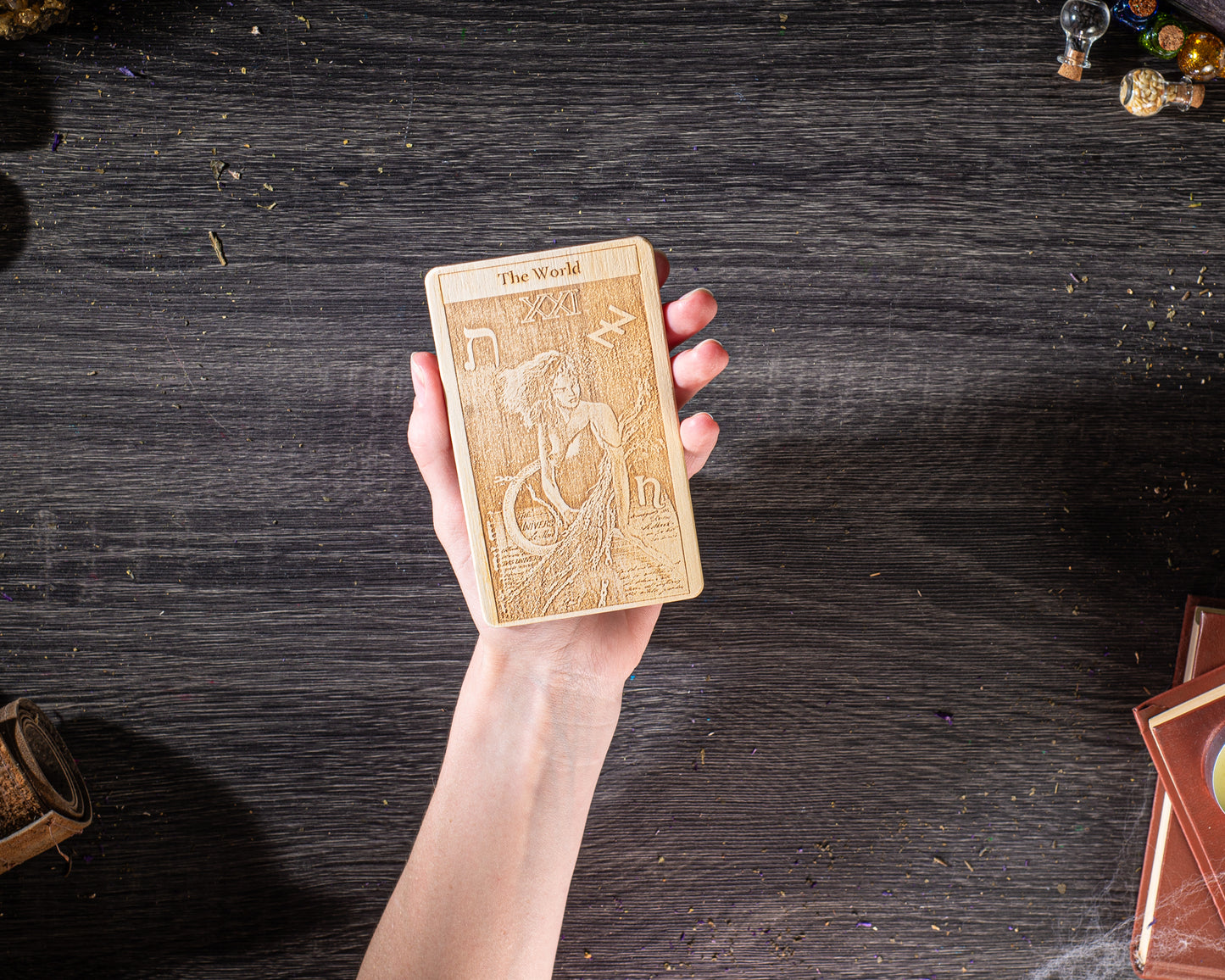 A hand holding a wooden card with an embossed design on it, placed on a wooden surface.
