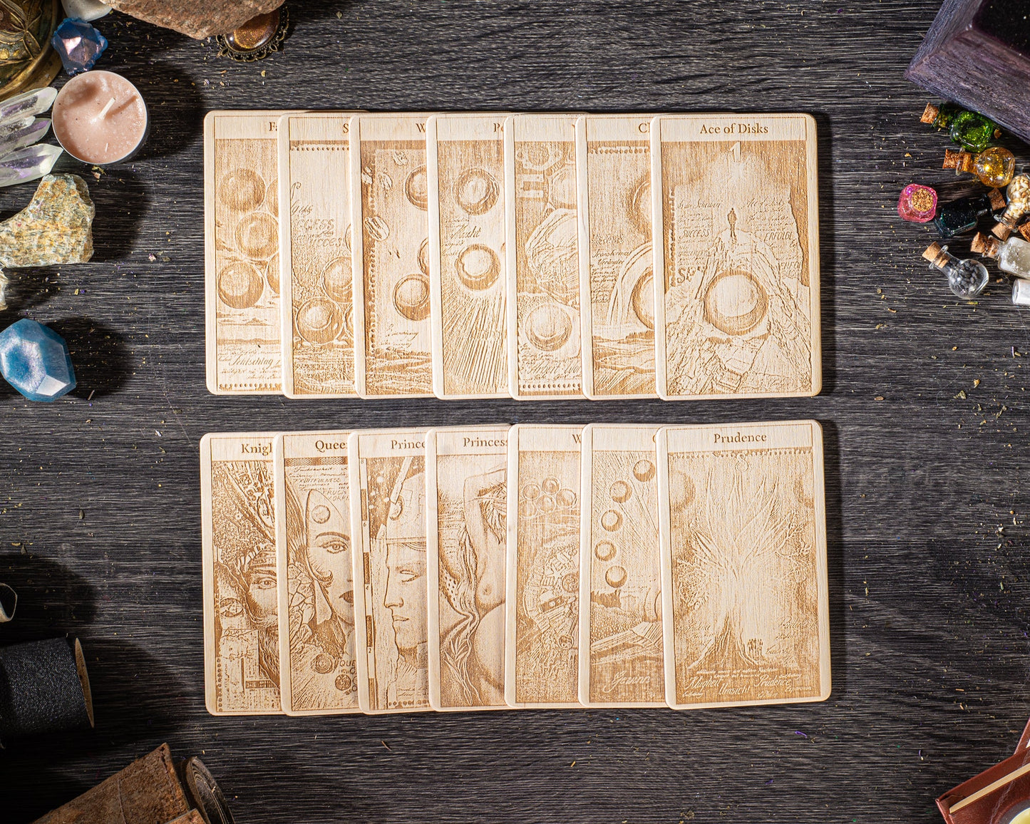 A collection of wooden tarot cards arranged on a dark wooden surface, with various objects scattered around them.