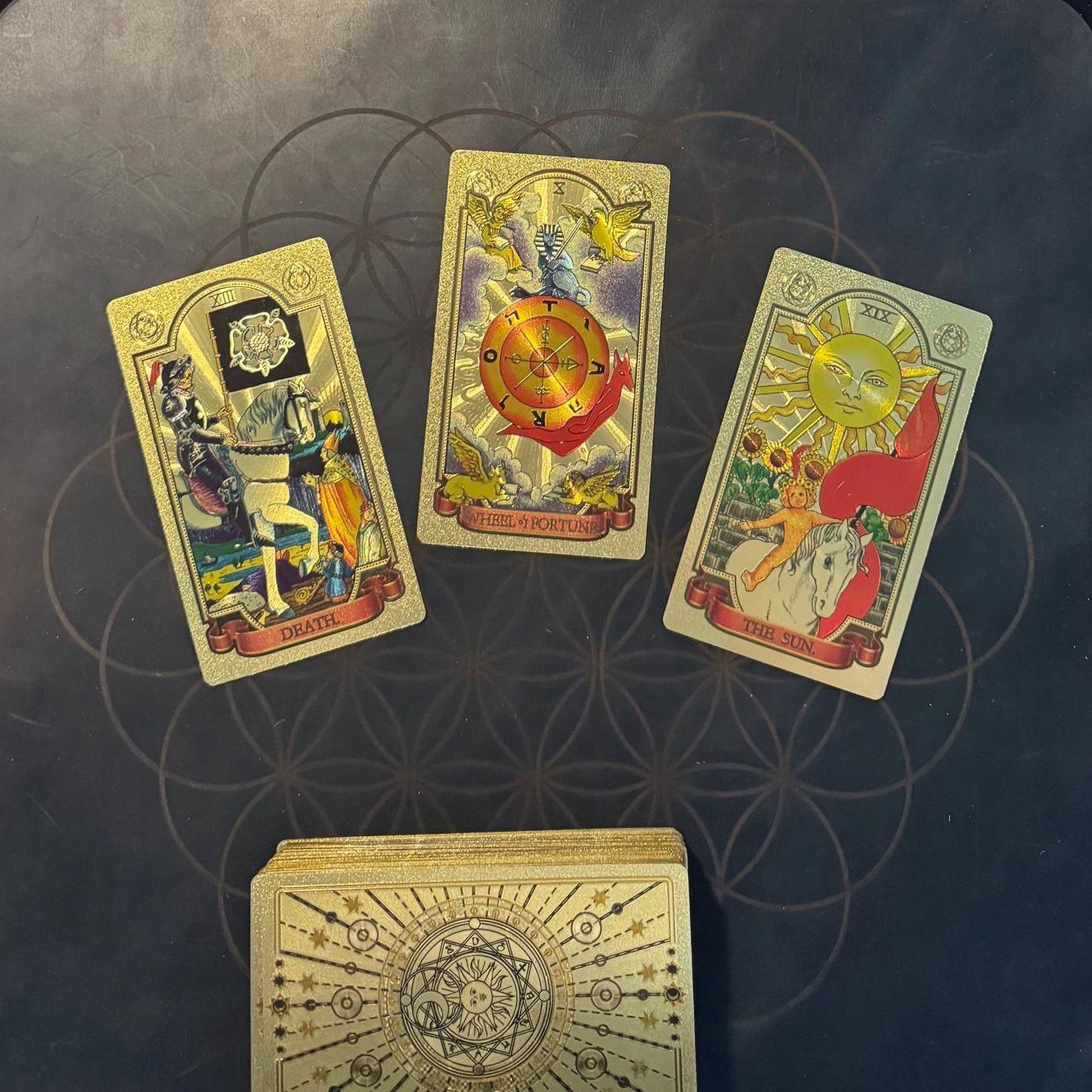 three tarot cards arranged on a dark background, with the central card being the largest and the other two cards positioned to the left and right of it.