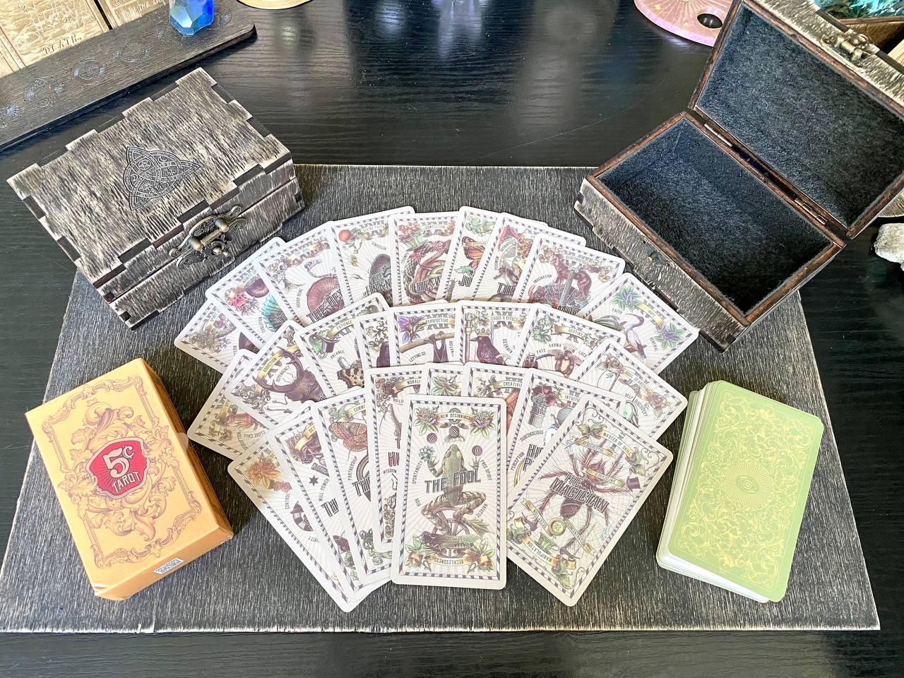 a collection of tarot cards and a wooden box on a wooden surface.