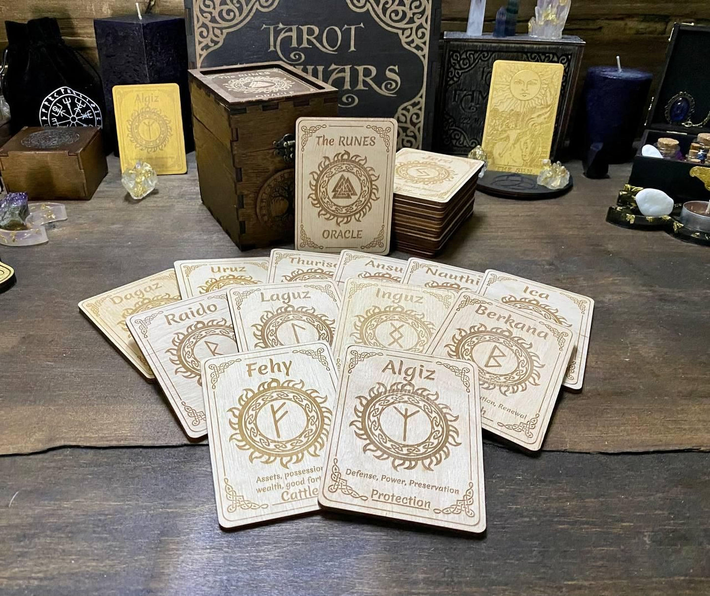 a collection of wooden tarot cards arranged on a wooden surface, with various other items such as crystals and candles in the background.