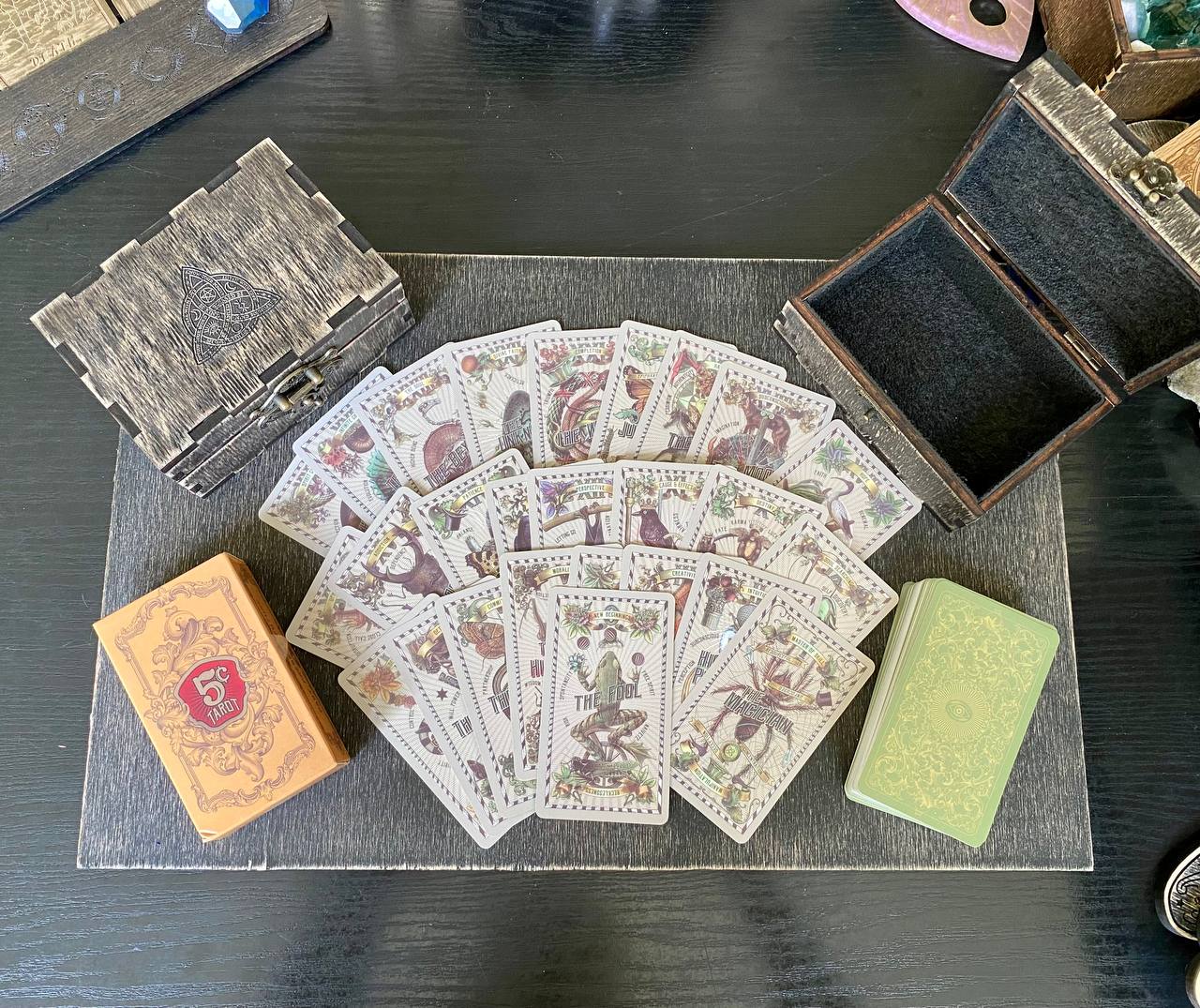 a collection of playing cards and tarot cards arranged on a wooden surface.