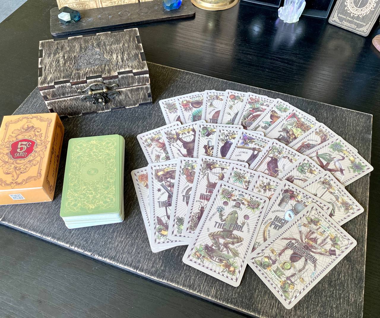 a collection of tarot cards and a wooden box on a wooden surface.