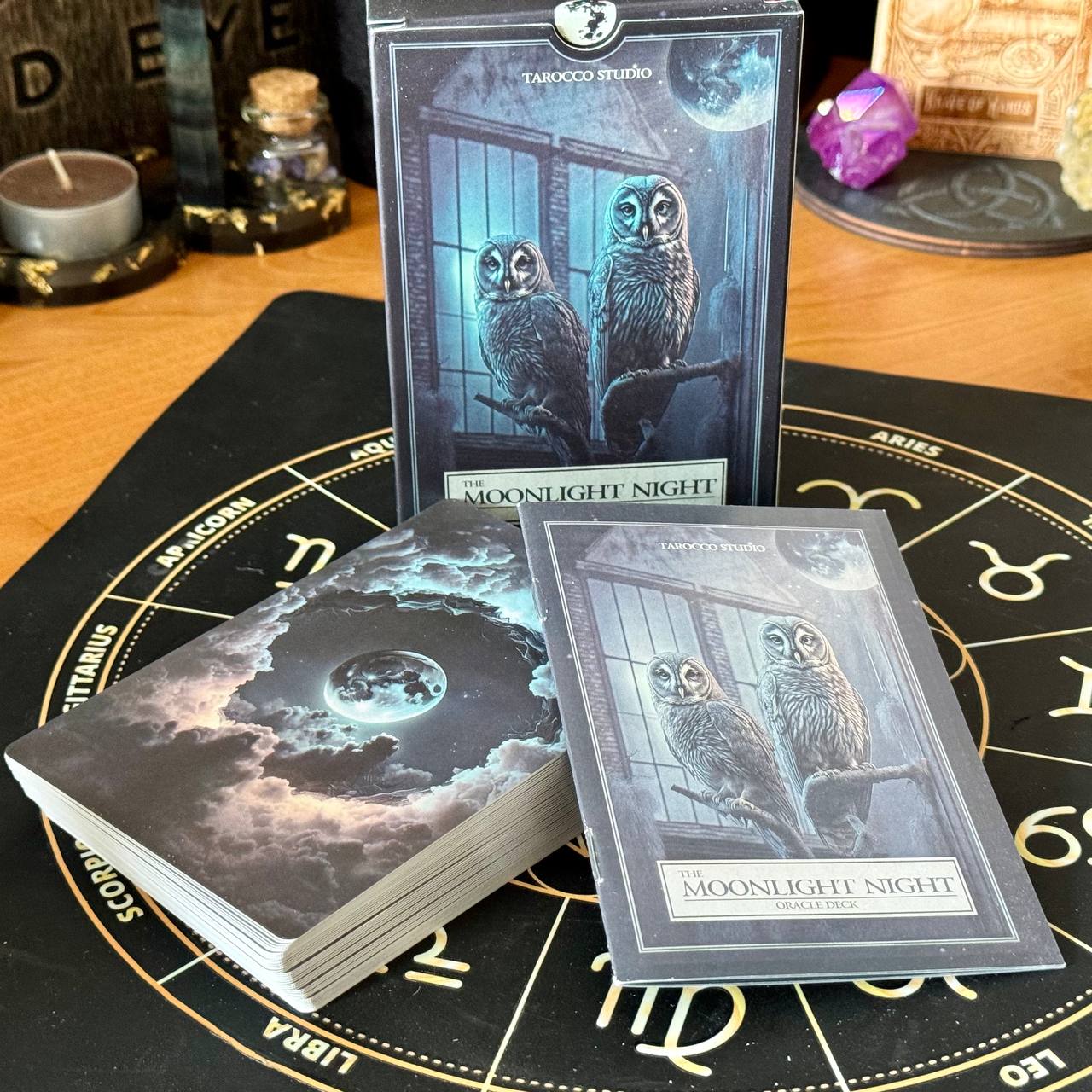 a tarot deck and a fortune teller's kit, both with owl illustrations, placed on a table.