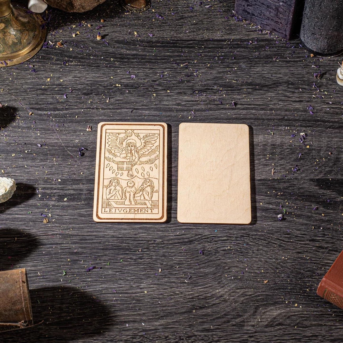 two wooden cards placed on a wooden surface, surrounded by various objects such as books and a lamp.