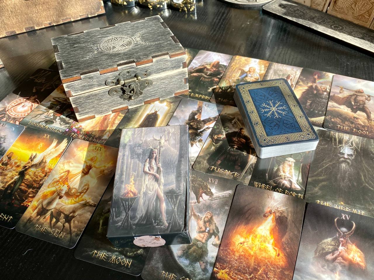 a collection of tarot cards and a wooden box with a dragon design on it, all placed on a wooden surface.
