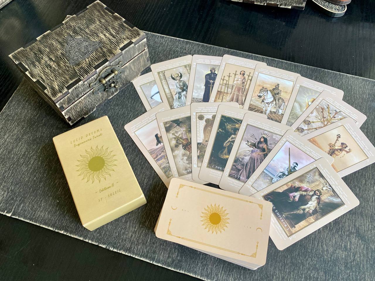 a collection of tarot cards and a wooden box, arranged on a gray surface.