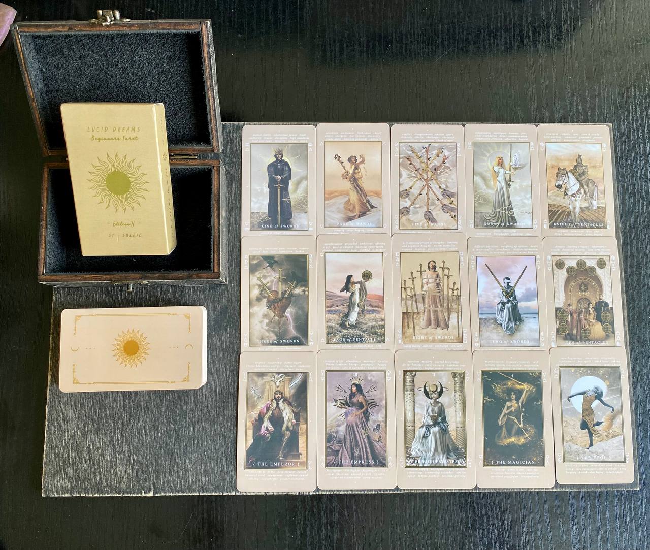 a collection of tarot cards and a box containing the cards, arranged on a wooden surface.