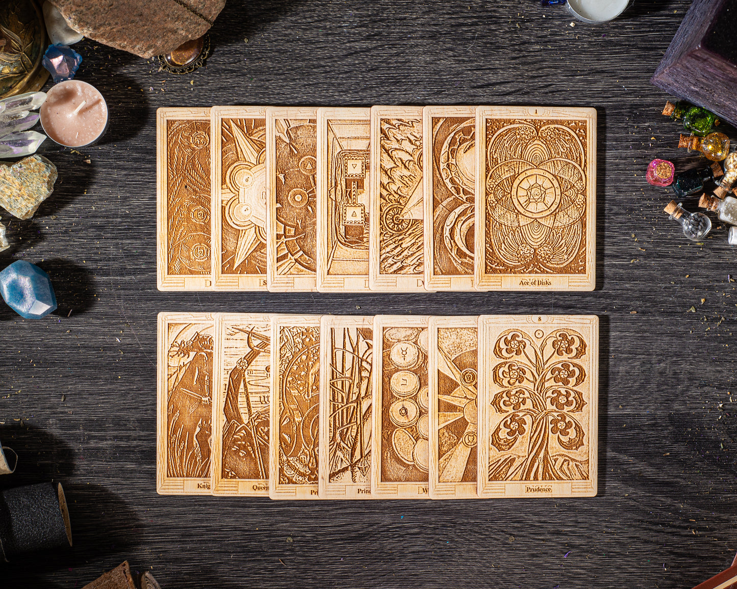 A collection of wooden tarot cards with intricate designs and illustrations, arranged on a dark wooden surface.