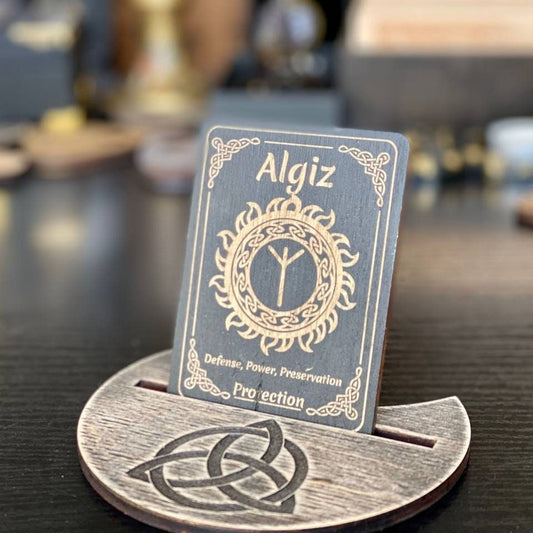 A wooden stand displaying a card with the name Algiz and a design featuring a sun and yin-yang symbol.