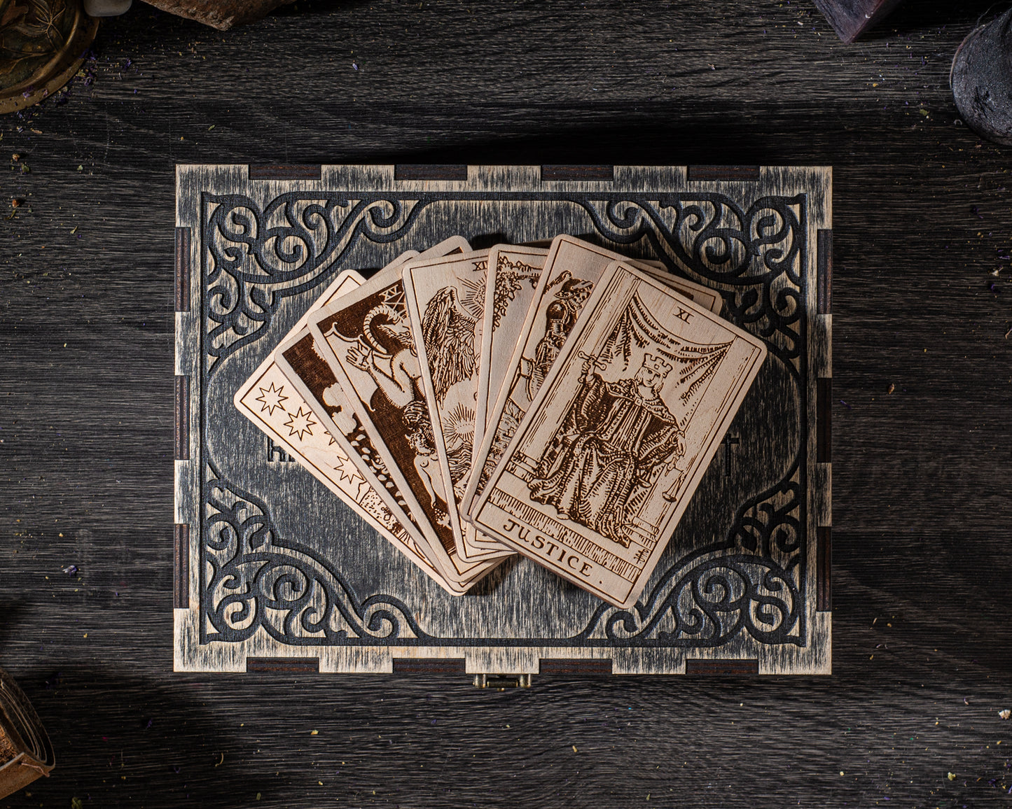 A deck of playing cards is displayed on a wooden box with an ornate, decorative border.