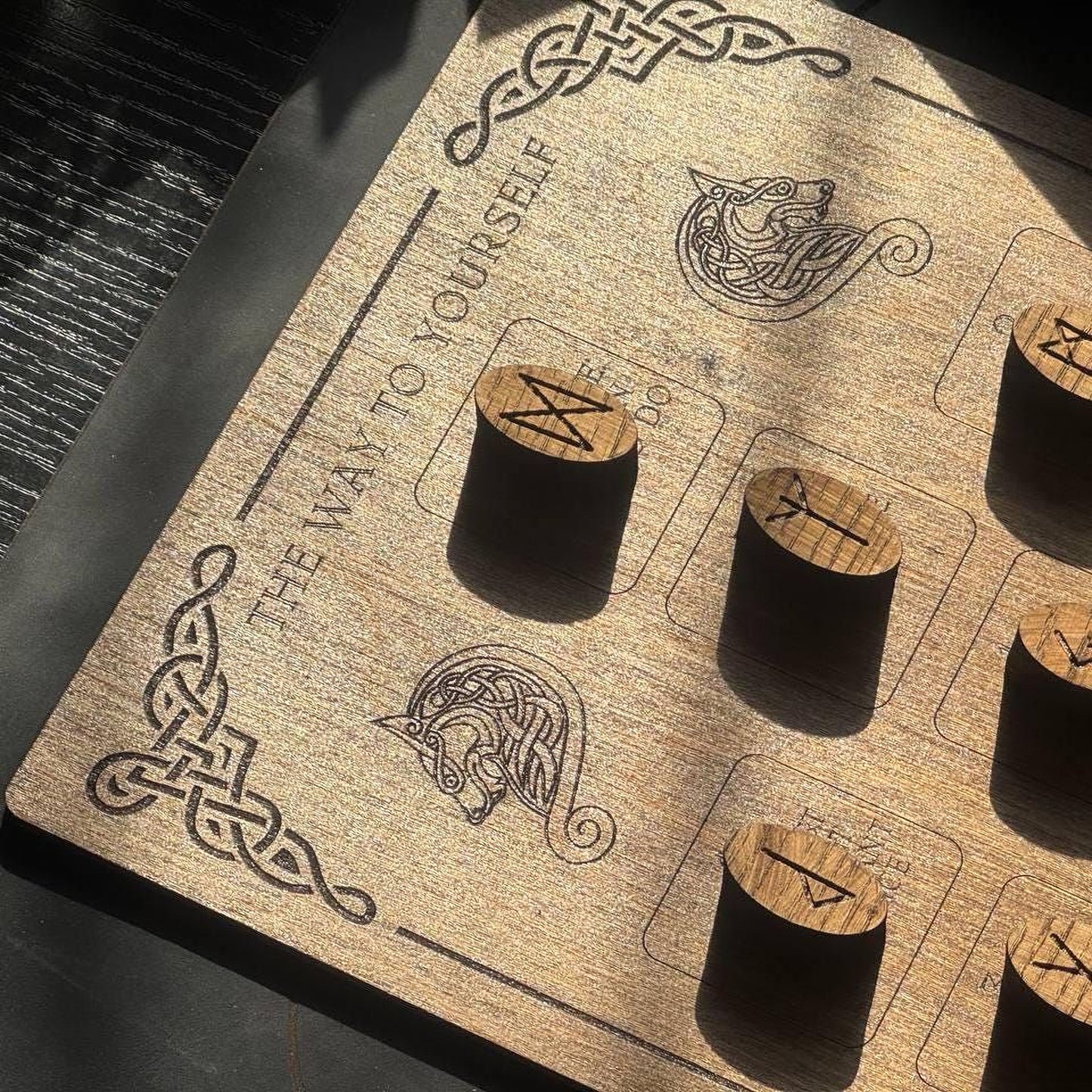 a wooden board with various symbols and text, including a dragon and a wolf, along with some carved wooden objects.