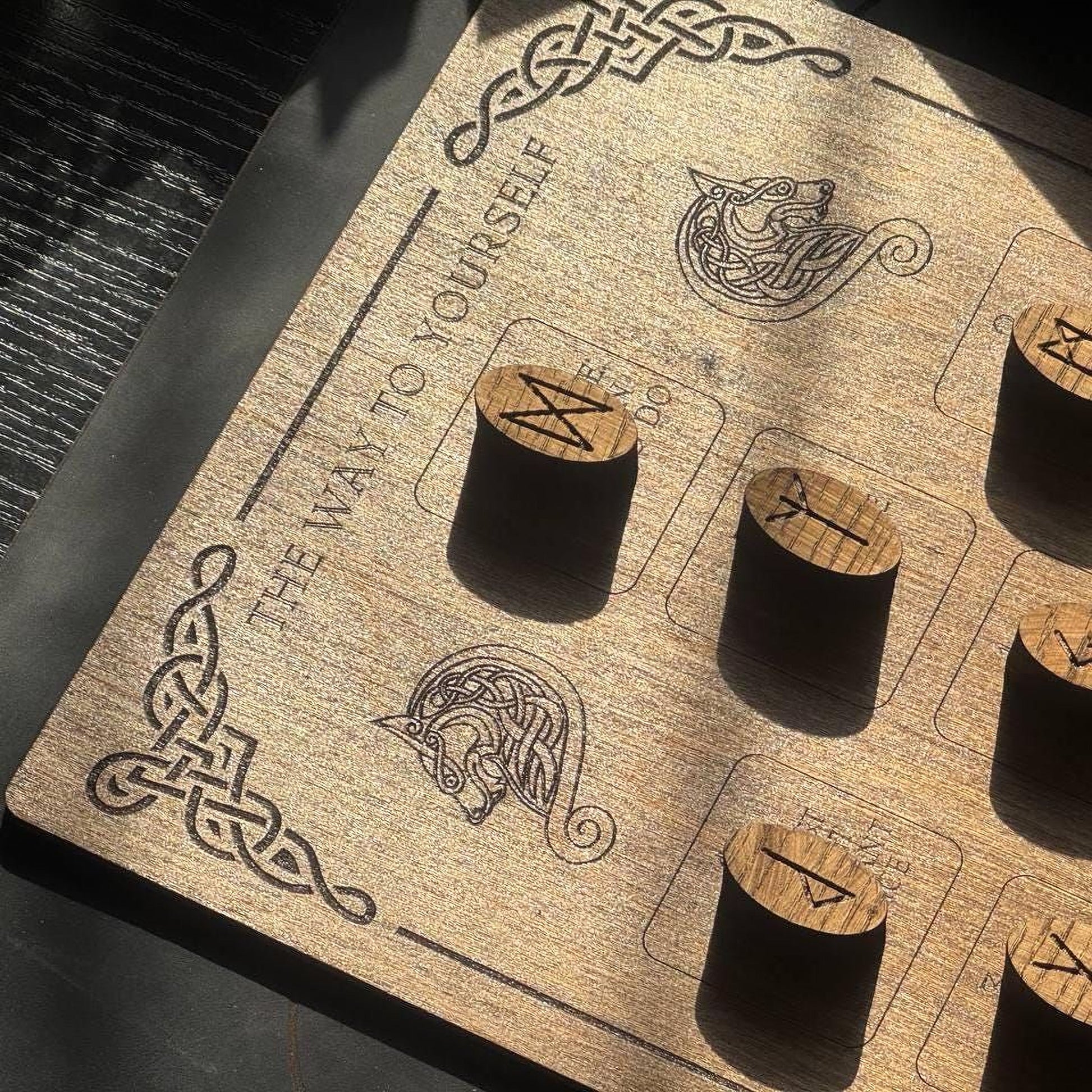 a wooden board with various symbols and text, including a dragon and a wolf, along with some carved wooden objects.