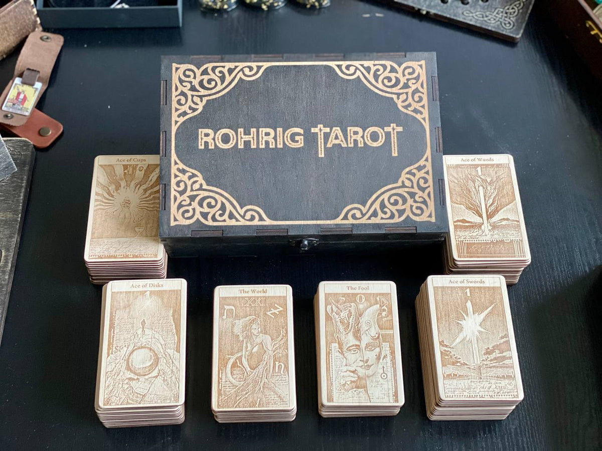 a collection of tarot cards arranged on a dark surface, with a wooden box containing the cards in the foreground.