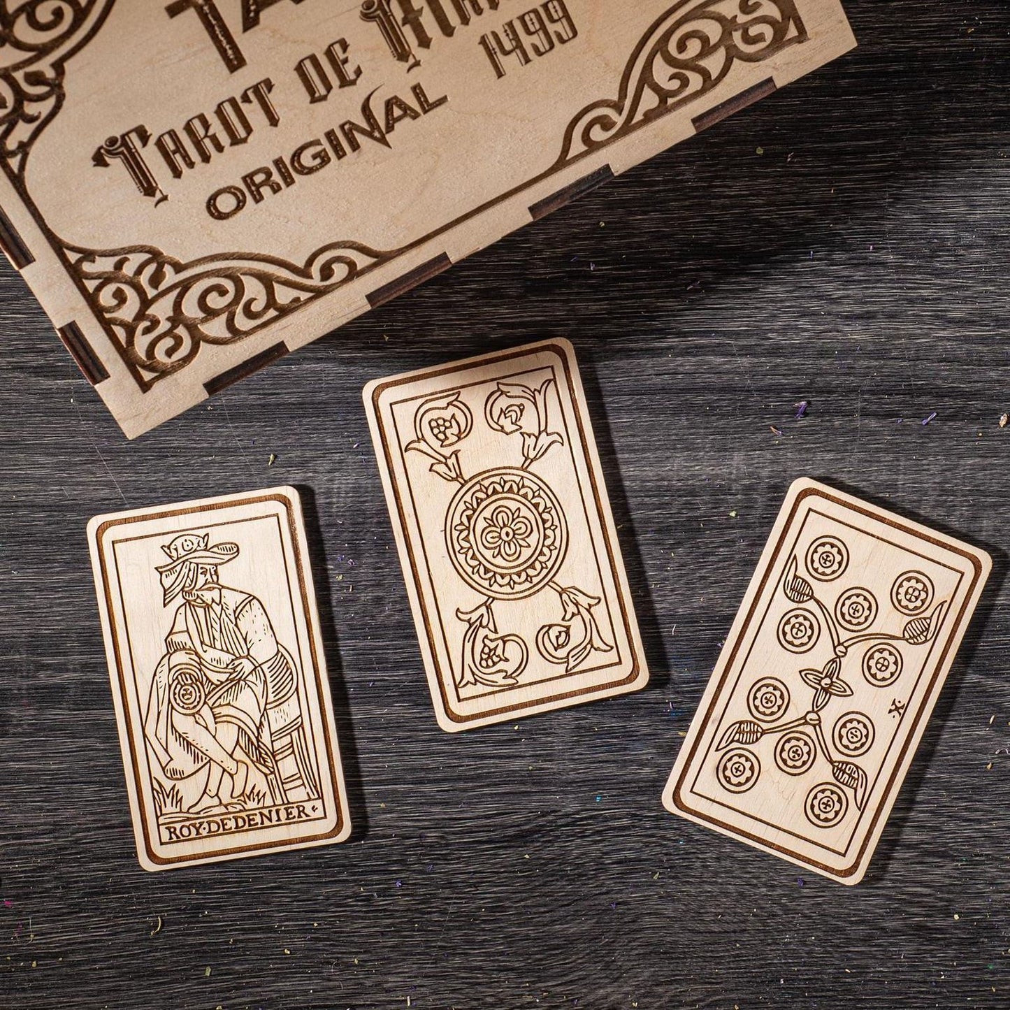 three wooden tarot cards with intricate designs, placed on a wooden surface.