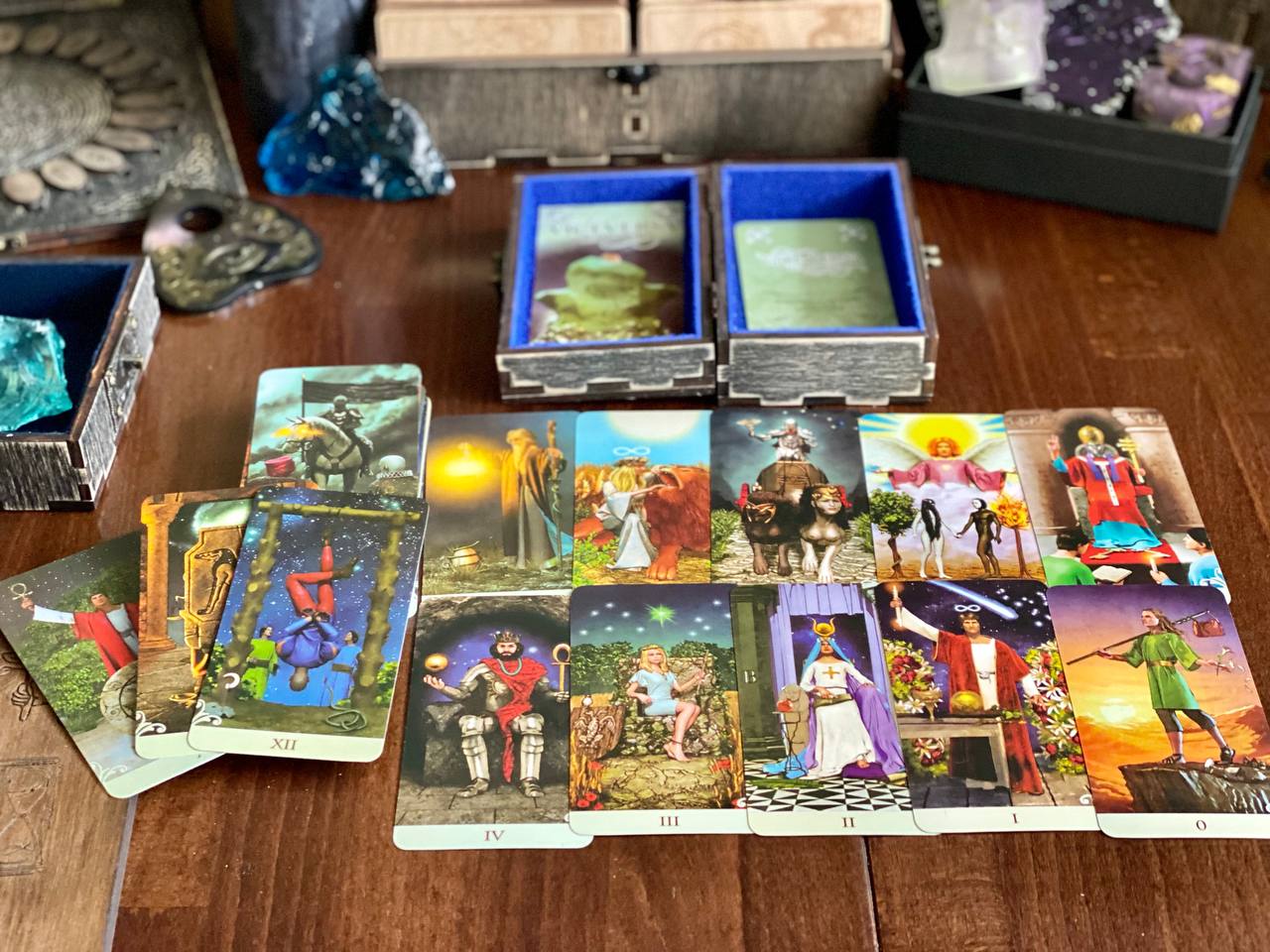 a collection of tarot cards spread out on a wooden surface, with some cards placed in open boxes.