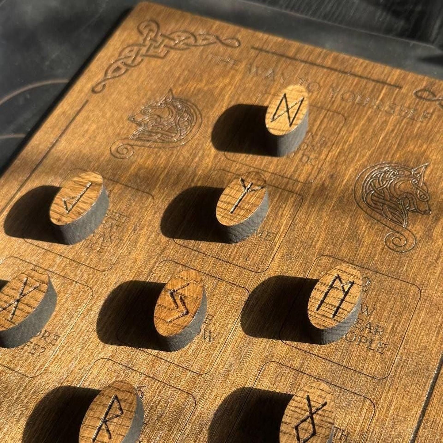 a wooden board with various wooden pieces engraved with symbols and text, likely representing a game or puzzle.