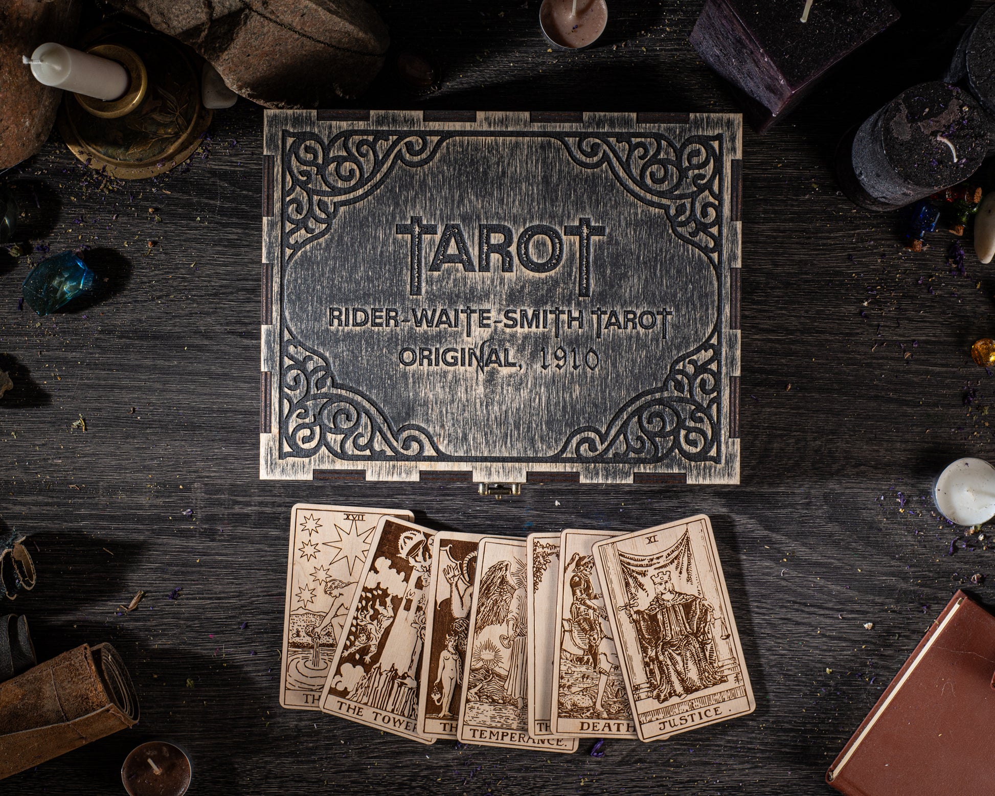 a tarot deck with a wooden box and a set of cards, all placed on a wooden surface with various objects scattered around.