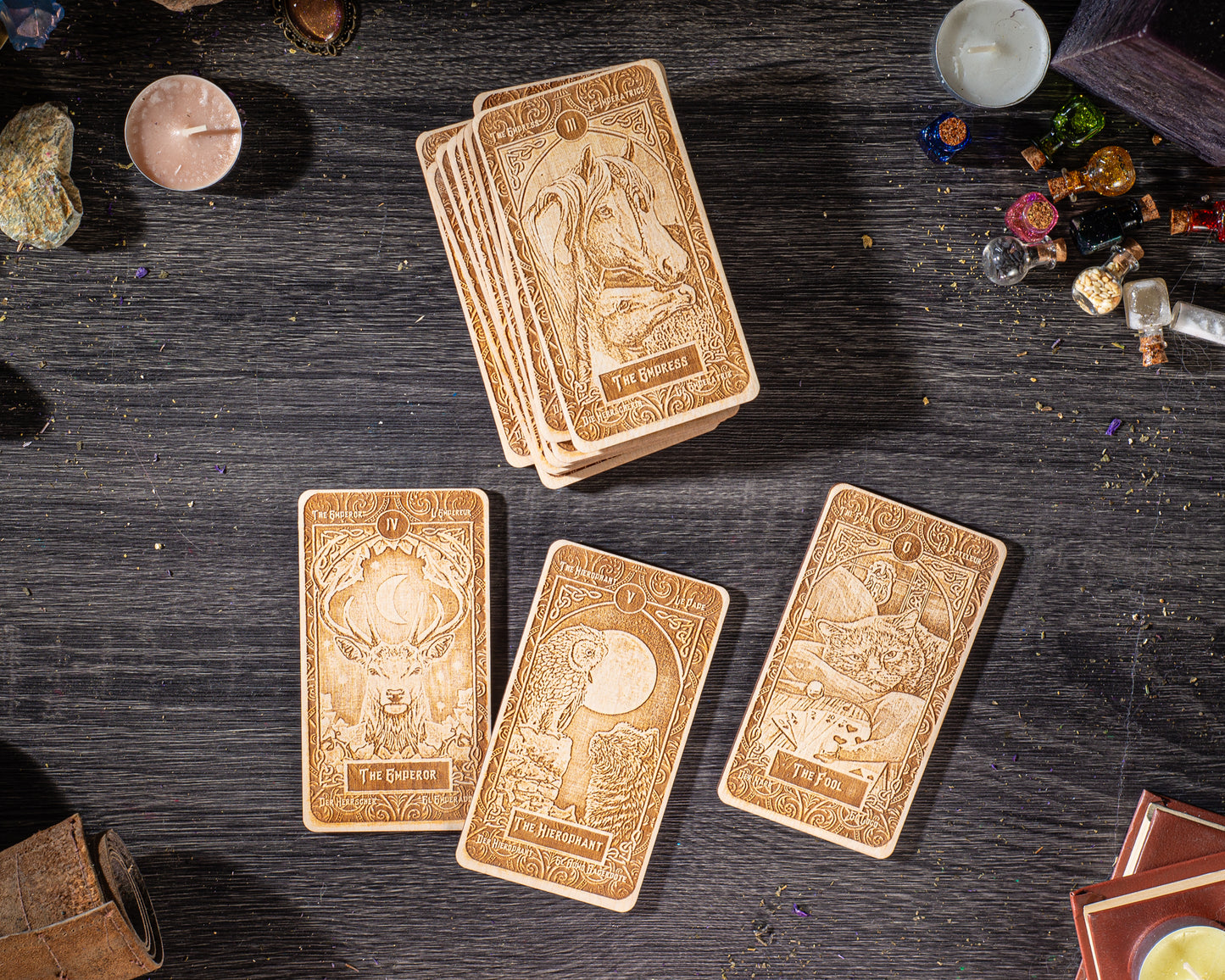 a collection of wooden tarot cards arranged on a wooden surface, along with various objects such as candles, crystals, and books.