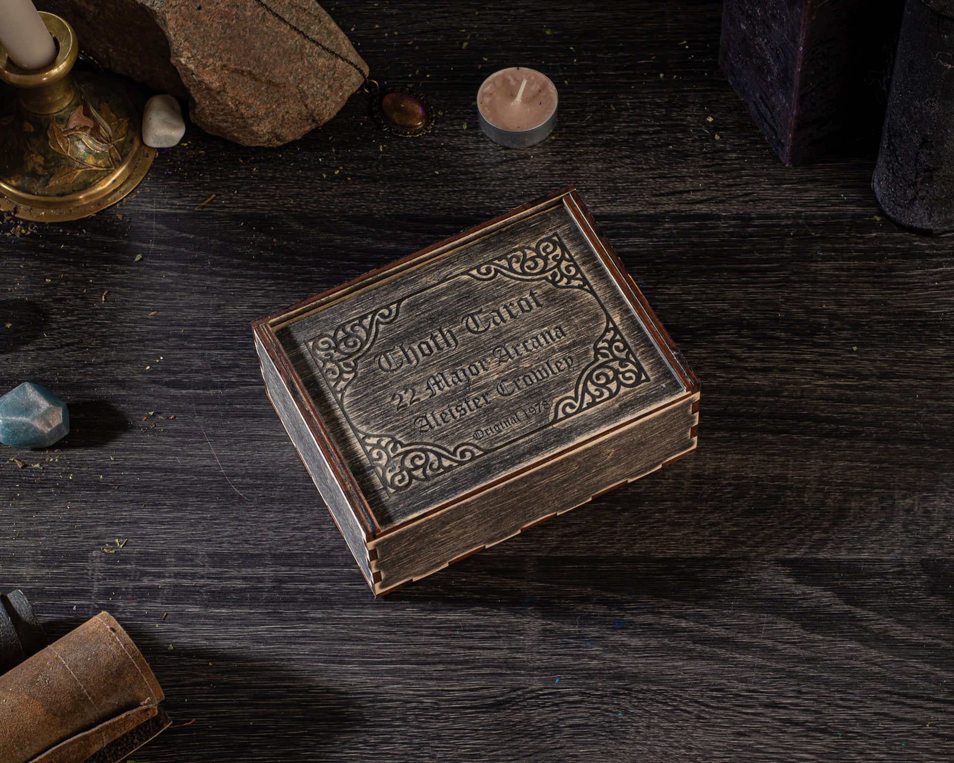 a wooden box with an ornate design, placed on a dark wooden surface.