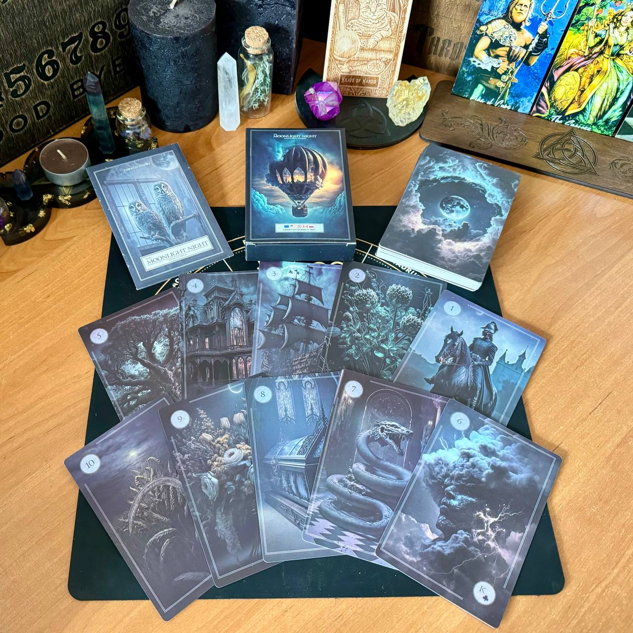 a collection of tarot cards spread out on a wooden surface, along with various crystals, candles, and other mystical objects.