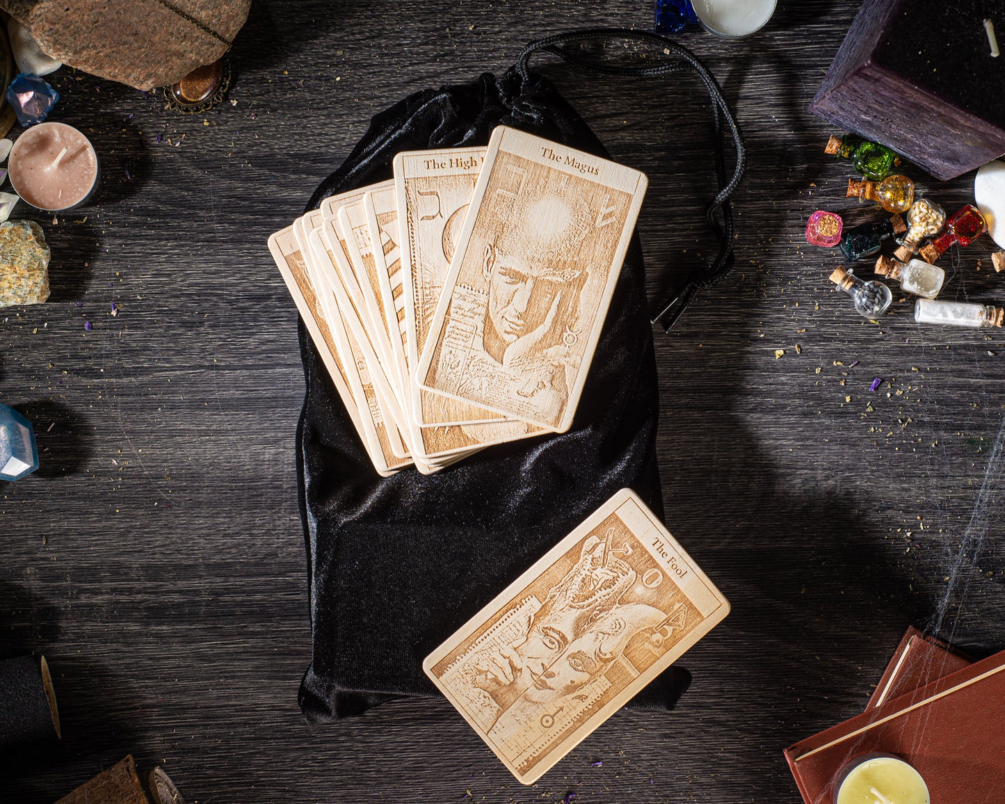 a collection of tarot cards and other items on a wooden surface, including a black velvet pouch and various small objects.