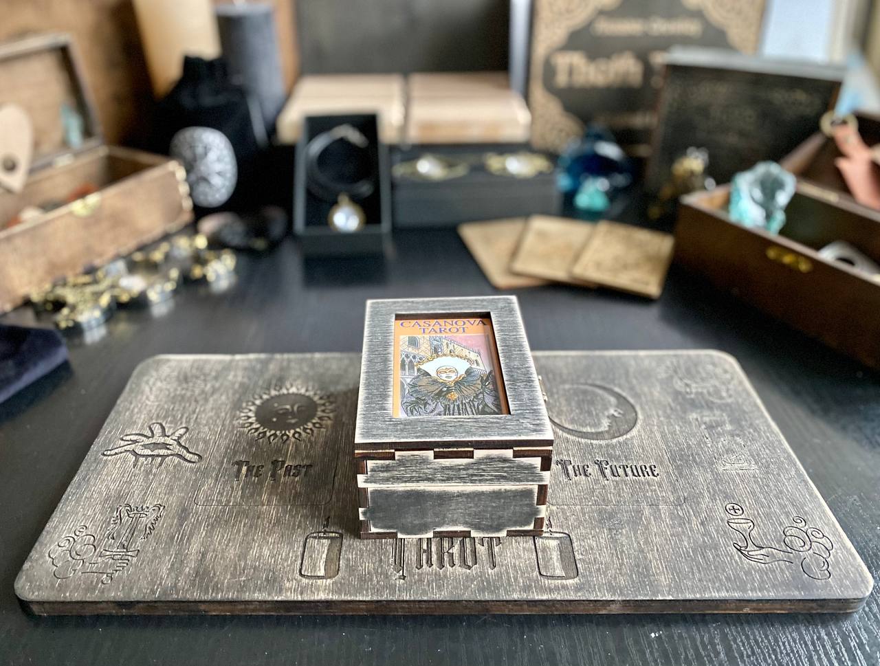 a wooden altar with various objects, including a tarot card box, a crystal, and a wooden box. The objects are arranged on a wooden surface, creating a rustic and mystical atmosphere.
