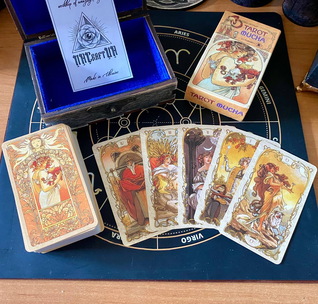 a collection of tarot cards and a wooden box, possibly containing additional cards or a tarot deck, arranged on a wooden surface.