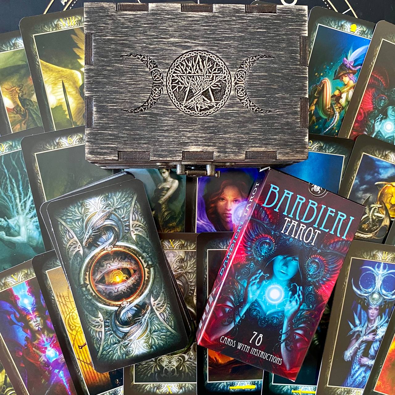 a collection of tarot cards and a wooden box with a design featuring a crescent moon and a star.