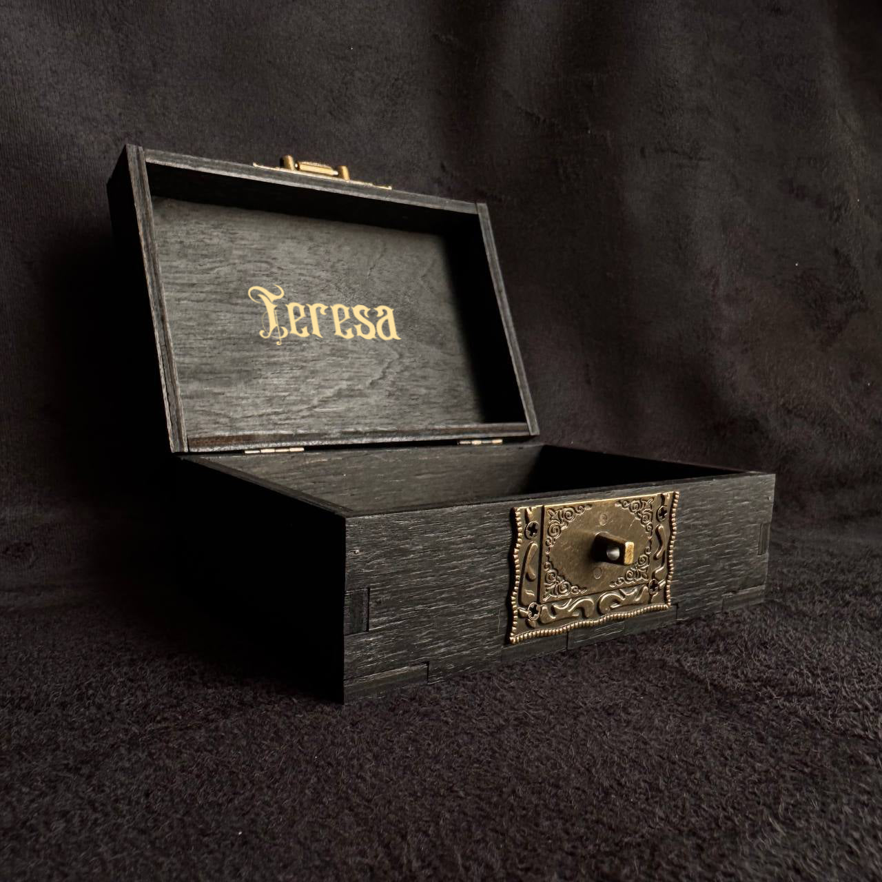 An open wooden box with the name "Lerasa" engraved on it, placed on a dark surface.