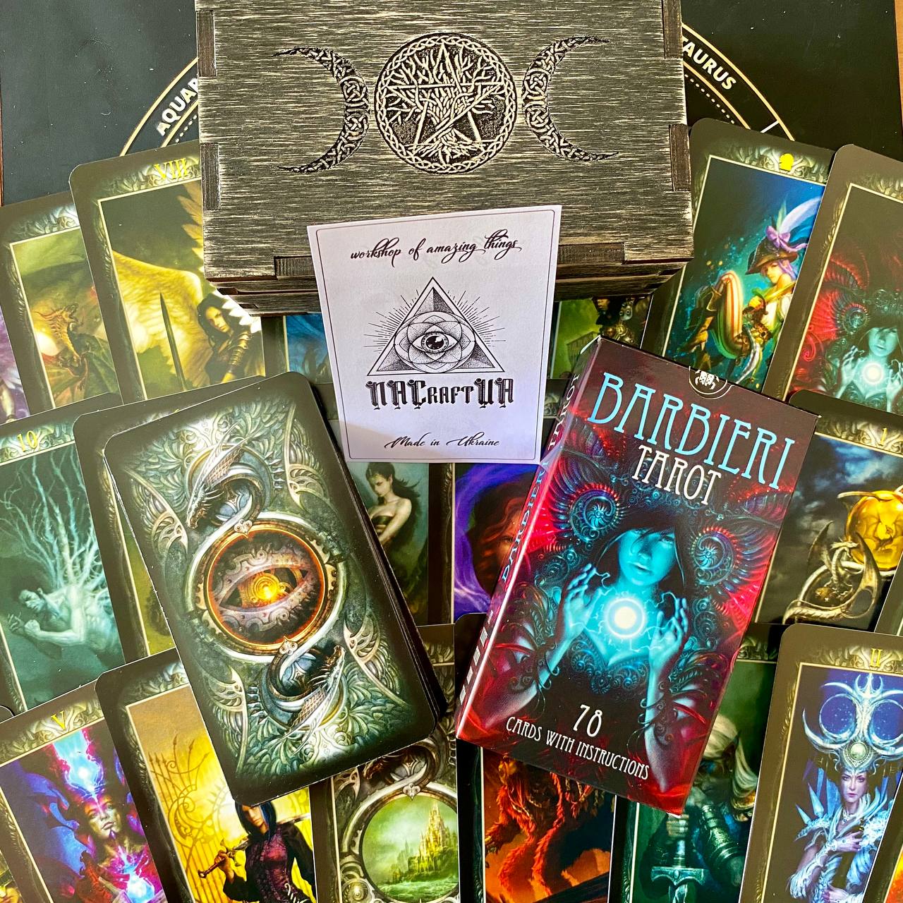 a collection of tarot cards and a wooden box with a design featuring a crescent moon and three crosses.