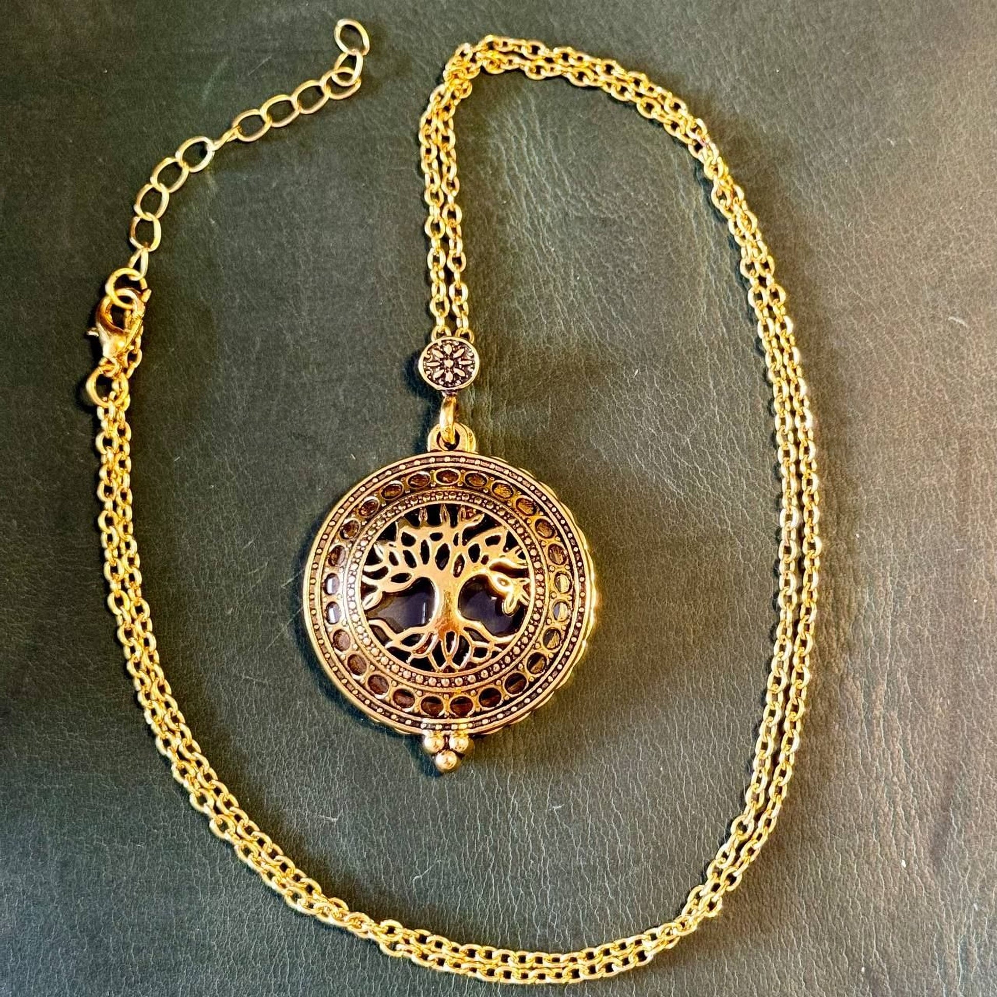 A gold-colored necklace with a circular pendant featuring a tree design.