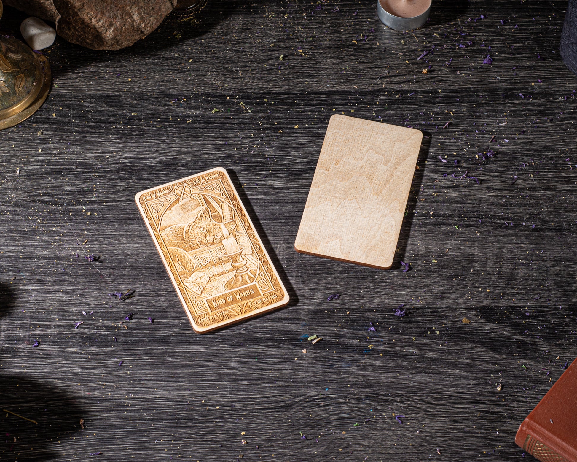 a wooden card with an embossed design, placed on a wooden surface with scattered purple flowers.