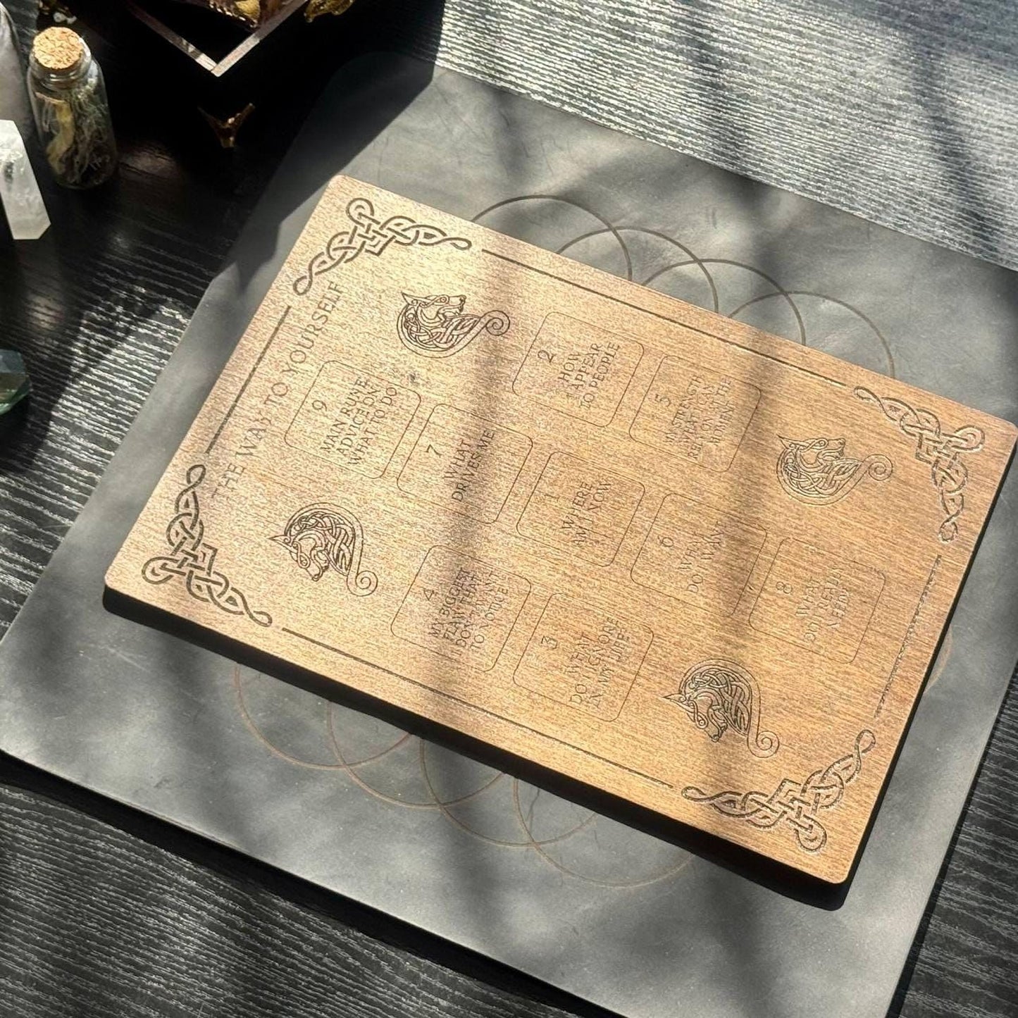a wooden board with intricate designs and text, placed on a dark surface.