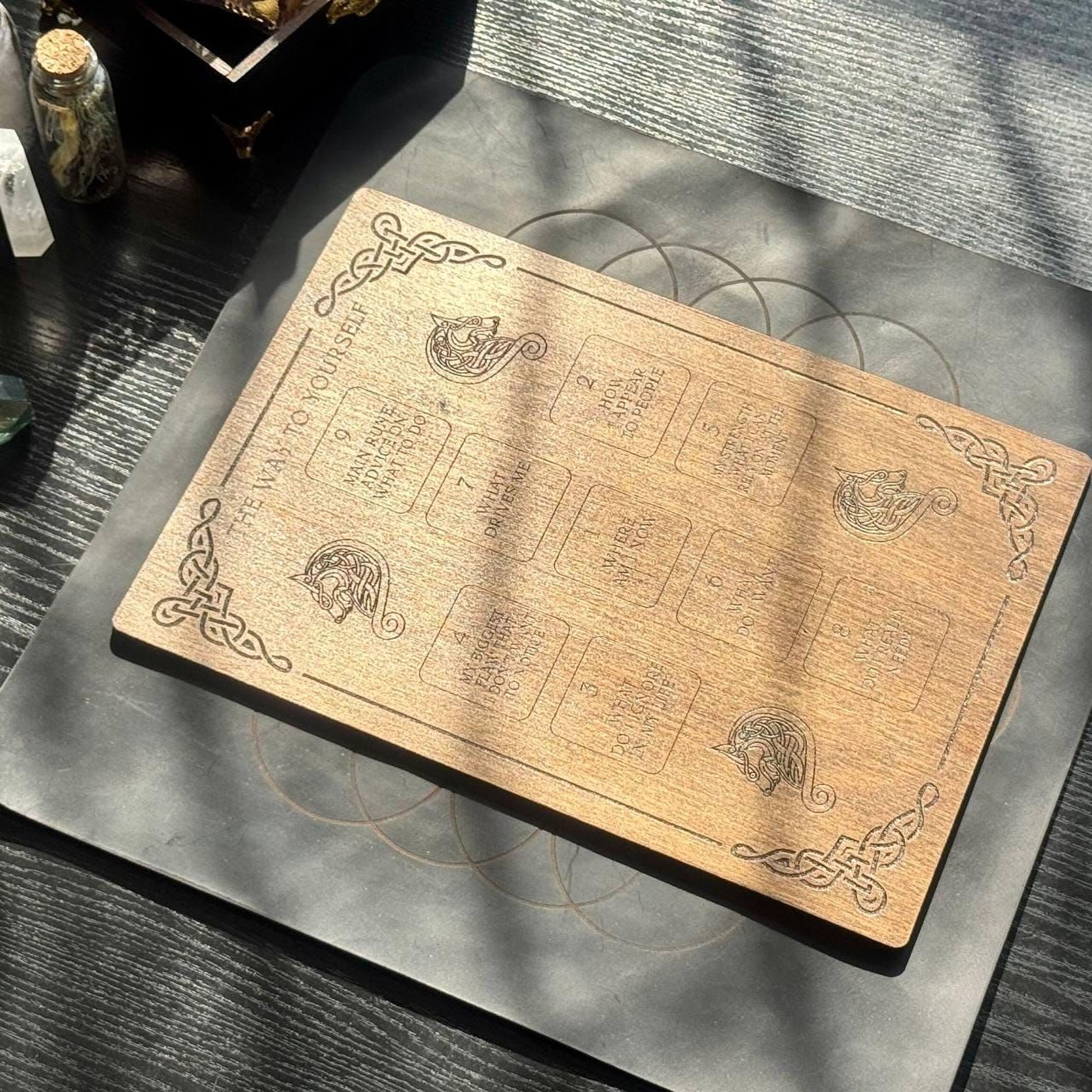 a wooden board with intricate designs and text, placed on a dark surface.