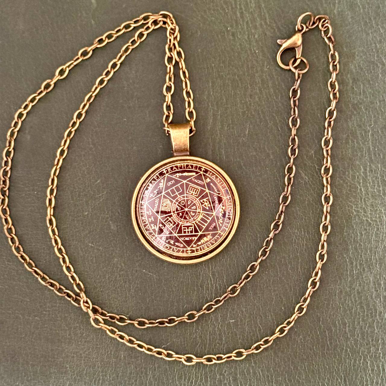 A gold-colored necklace with a circular pendant featuring a geometric design.